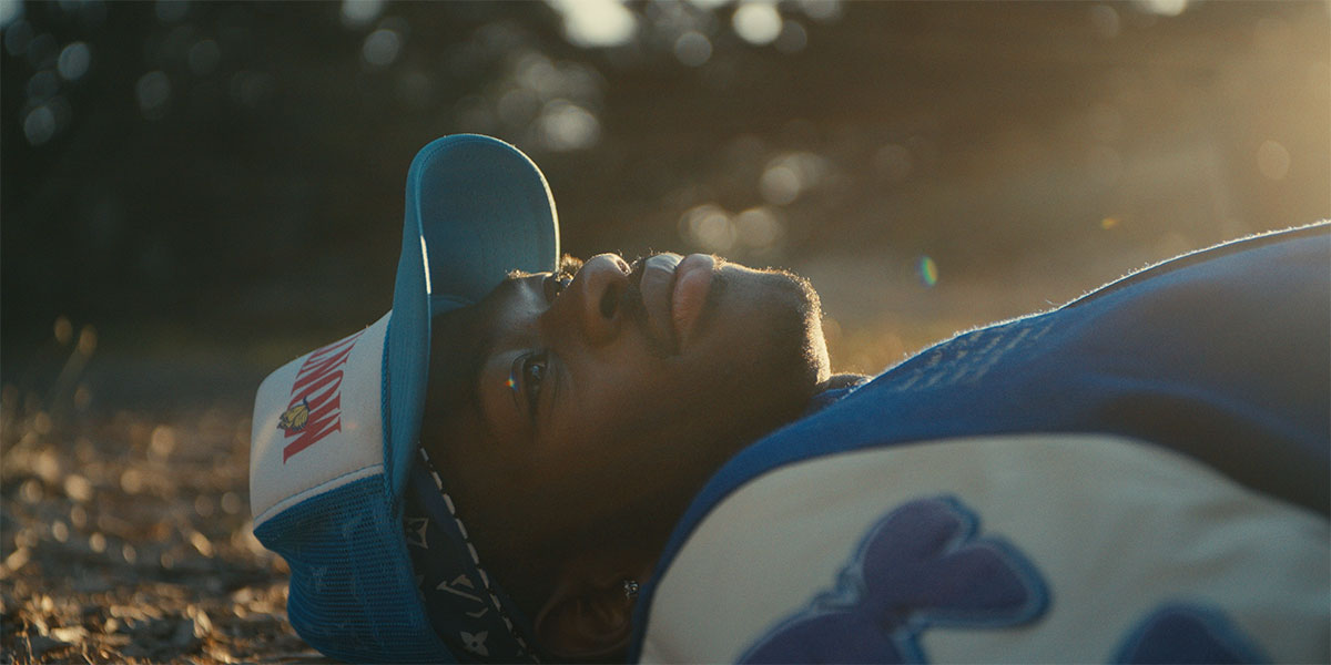 GRAMMY award-winning rapper, singer and songwriter, Lil Nas X lying down on a grassy field looking up into the sky