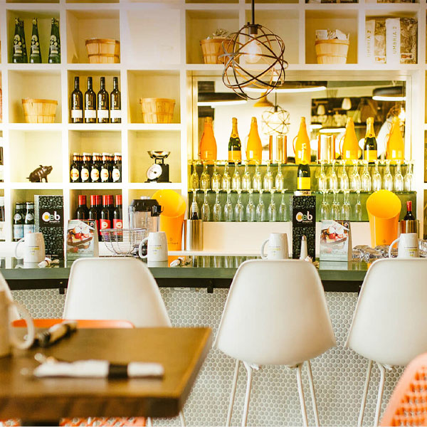 Modern restaurant interior with marble walls, blue shelving, pendant lights, and plush velvet seating