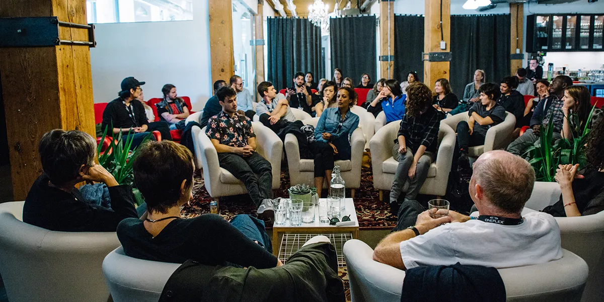 Diverse audience seated in modern industrial space with wooden pillars, watching presentation or event