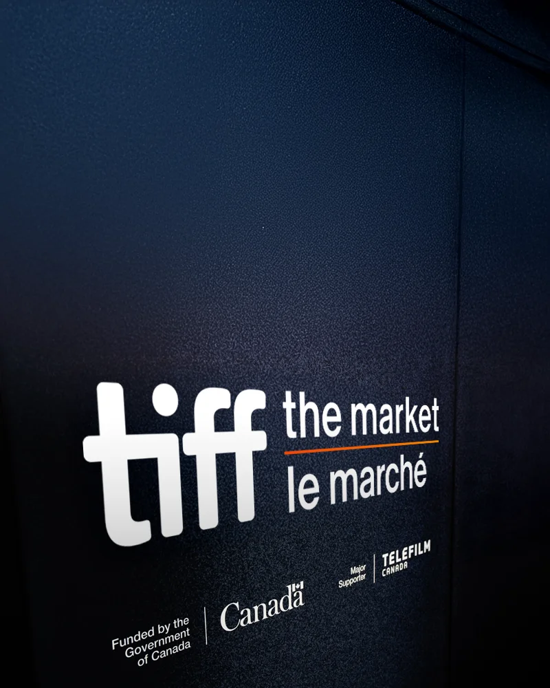 Fond bleu marine foncé affichant le logo du TIFF : Le Marché en blanc, avec les logos des commanditaires Canada et Téléfilm Canada.