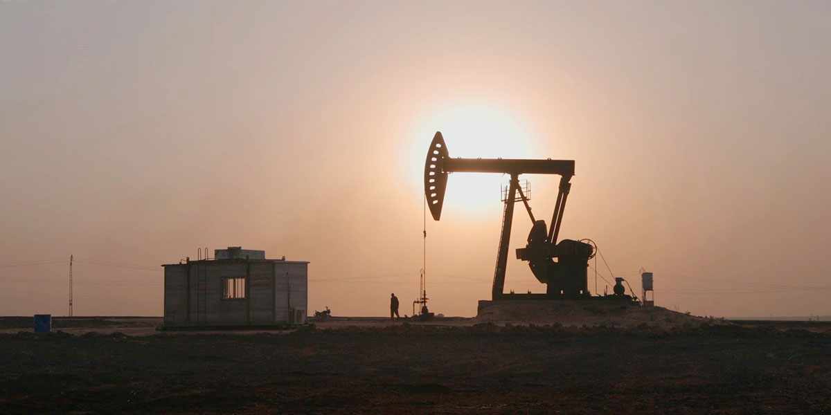 A sunset against an oil drill in the desert