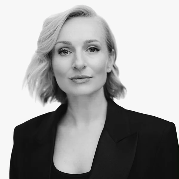 Black and white professional headshot of a woman with short wavy hair wearing a dark blazer.
