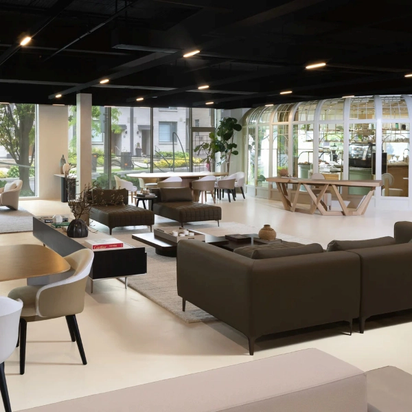 The showroom of Atriani Interiors, featuring minimalist furniture, light-colored floors, and an industrial dark ceiling.