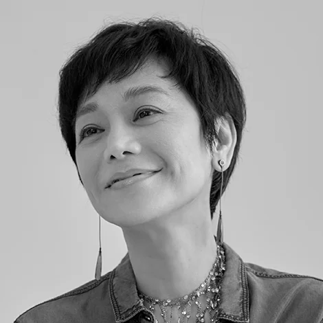 Black and white portrait of a smiling middle-aged woman with short dark hair and dangling earrings.