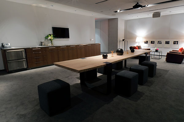 Interior shot of The Green Room with a long wooden table and black cube stools around it