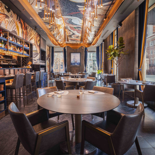 Modern restaurant interior with marble walls, blue shelving, pendant lights, and plush velvet seating