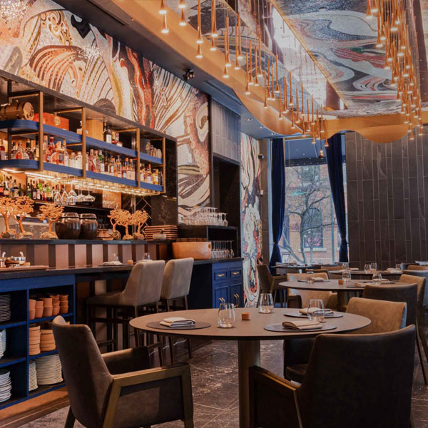 Modern restaurant interior with marble walls, blue shelving, pendant lights, and plush velvet seating