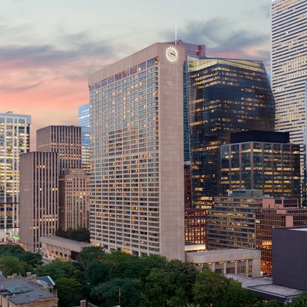 Downtown Toronto skyline at sunset with illuminated office towers and Sheraton hotel against a pink sky