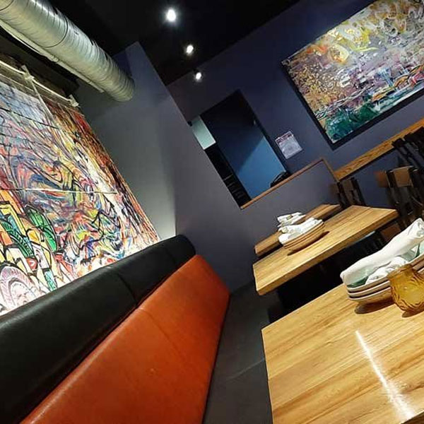 Modern restaurant interior with colorful graffiti art, leather booth seating, and wooden tables