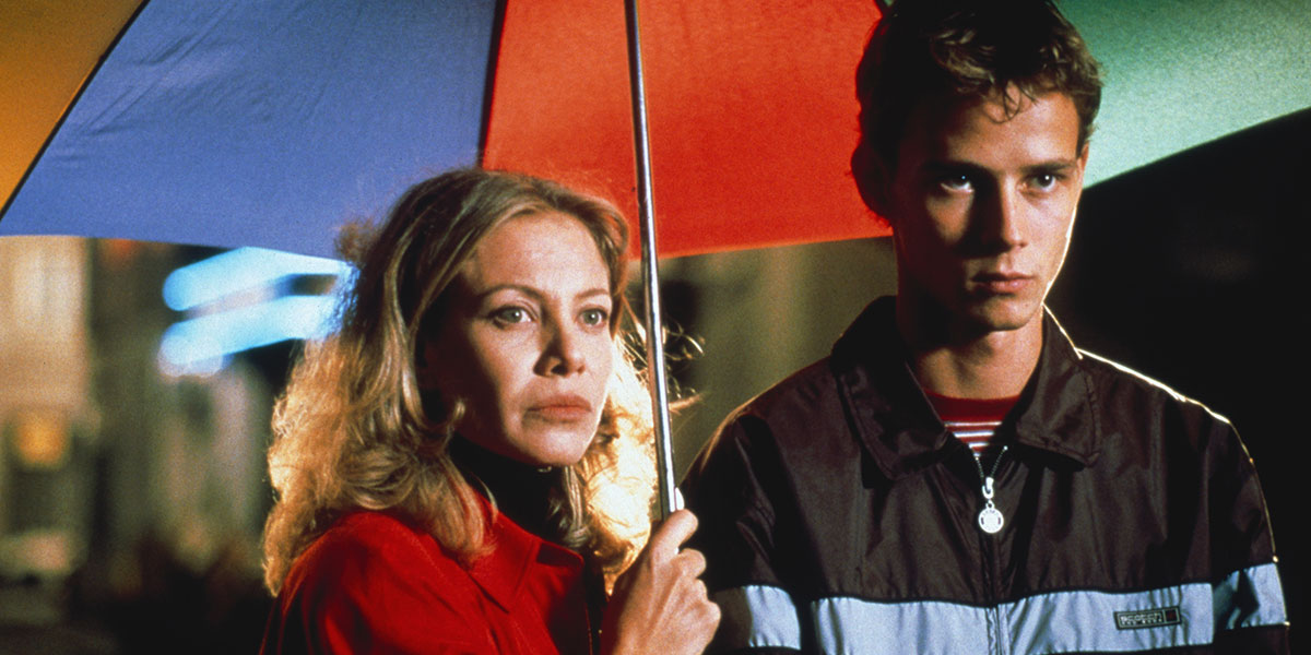 A woman holding a rainbow umbrella for her and her son