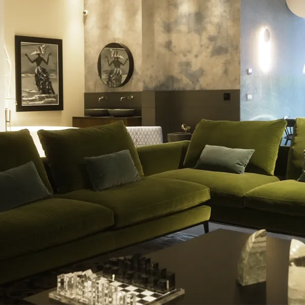 Modern living room with plush green velvet sofas, black framed artwork, and a chess set on coffee table