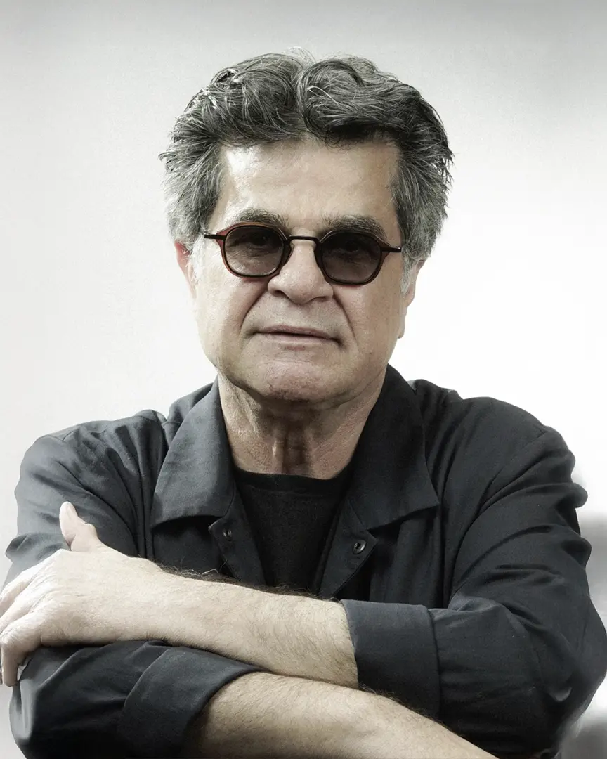 Close-up portrait of a mature man with gray hair wearing dark sunglasses and a black shirt against white background