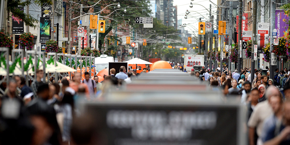 Looking down a busy Festival Street with signage up the middle of the road amongst the sea of people