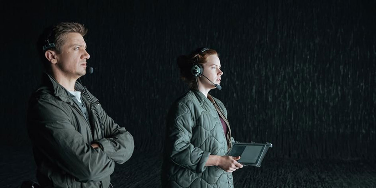 Amy Adams and Jeremy Renner looking towards the light in a dark room