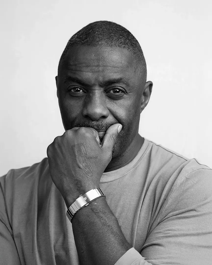 Black and white portrait of a contemplative man in a t-shirt with his hand near his mouth, wearing a metal watch