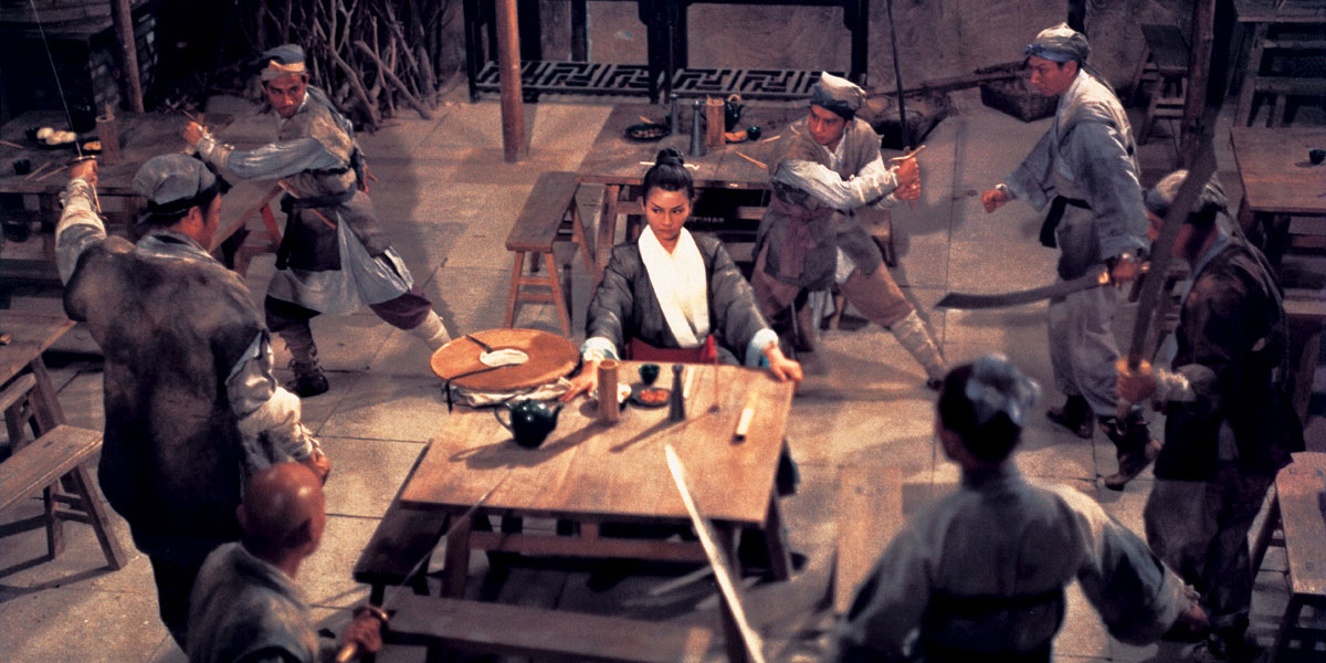 A Chinese female warrior in a bar surrounded by men with swords drawn towards her