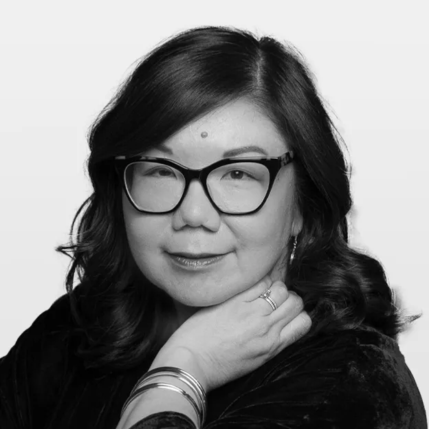 Professional headshot of Judy Lung with black-rimmed glasses and long, dark wavy hair