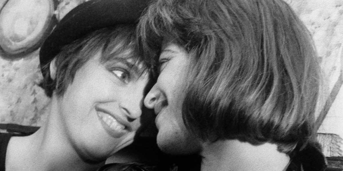 Black and white photo of two young people leaning close together, smiling intimately.