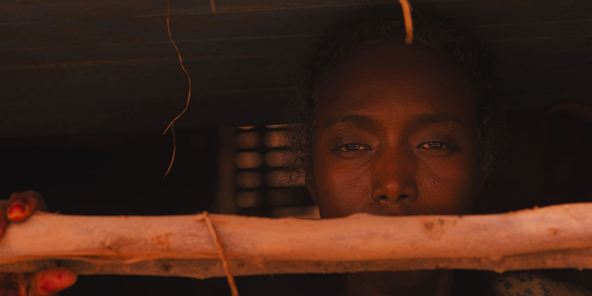 A Somali woman peering out from the window towards the camera