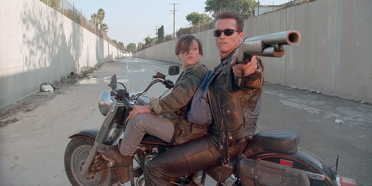 T-800 (Arnold Schwarzenegger) on a bike while pointing a shotgun towards the camera