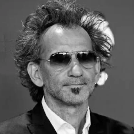Black and white portrait of a man with tousled hair, aviator sunglasses, and a soul patch beard.