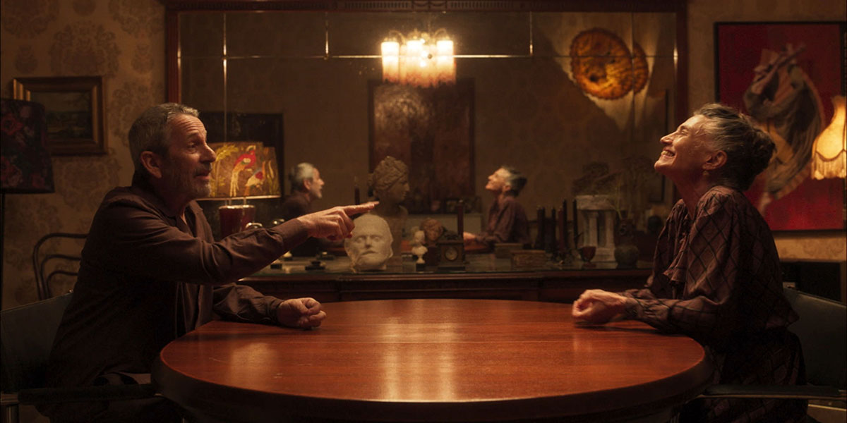 An elderly couple sitting across one another in a circular table within an dining room