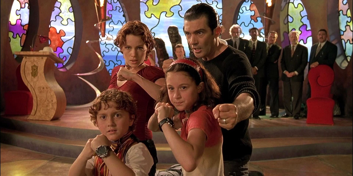 A family of four in fighting stances inside a colorful, puzzle-themed room with stained glass arches.