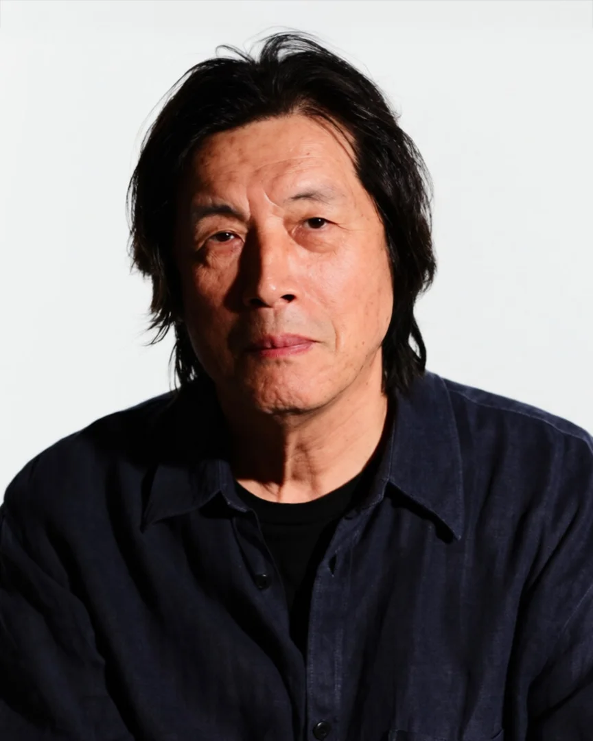Black and white portrait of an older Asian man with long dark hair wearing a dark shirt.