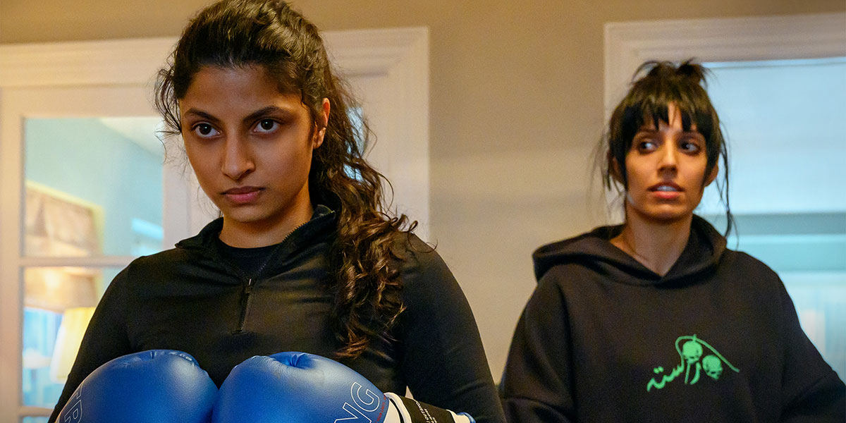 Ria (Priya Kansara) in boxing gloves while Lena (Ritu Arya) stands behind her