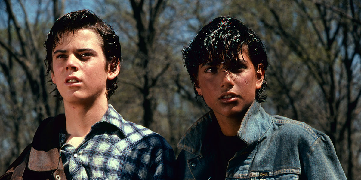 C. Thomas Howell and Ralph Macchio in a forest looking beyond the camera