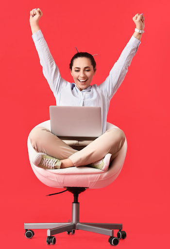 Developer in chair with a laptop in their lap, arms raised in victory.