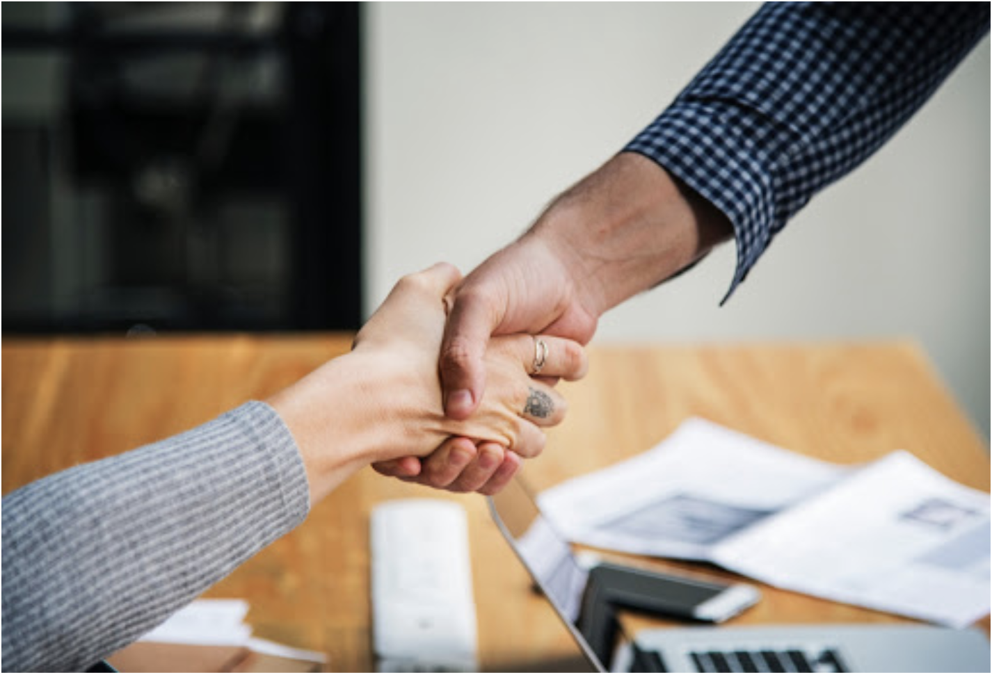 Two people shaking hands in office environment