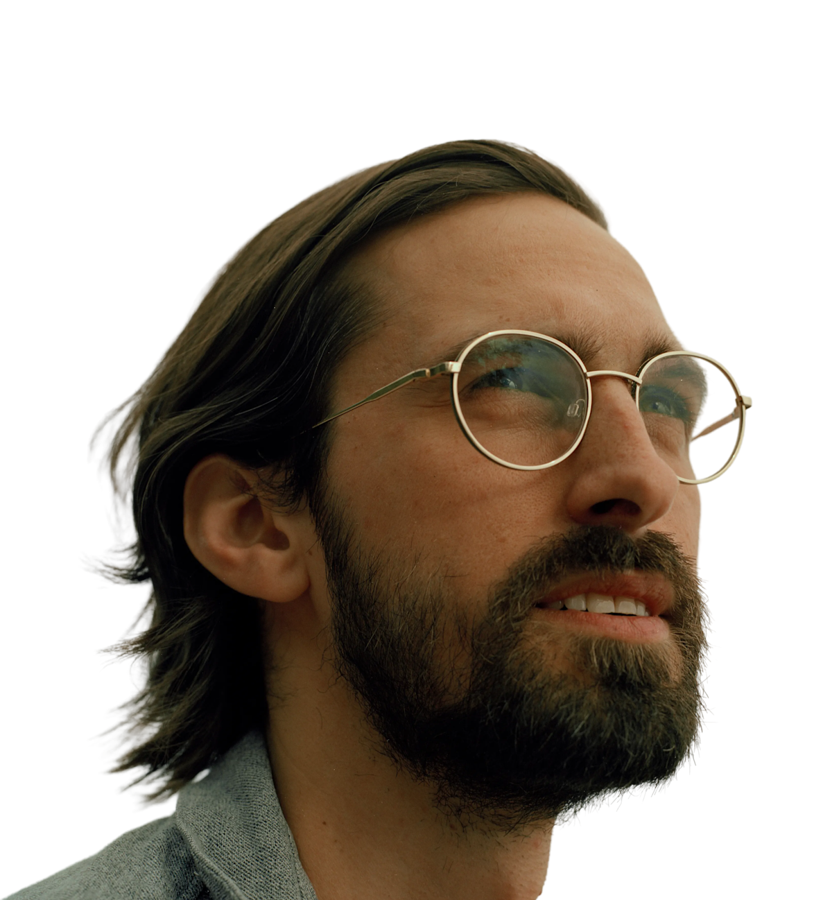 A man wearing round glasses looking into the distance.