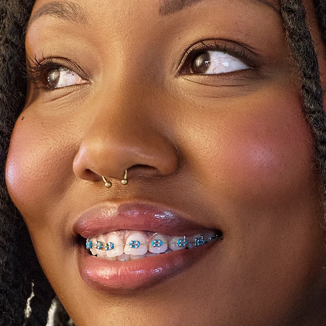 A close up of a woman with a nose ring and braces