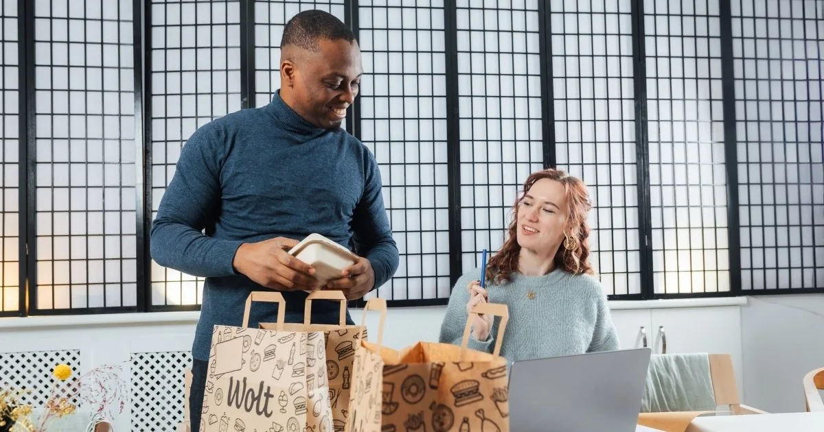 Zwei Kollegen packen eine Wolt-Essenslieferung am Arbeitsplatz aus – ein Beispiel dafür, wie Lieferplattformen Restaurants mit Kunden über den Gastraum hinaus verbinden