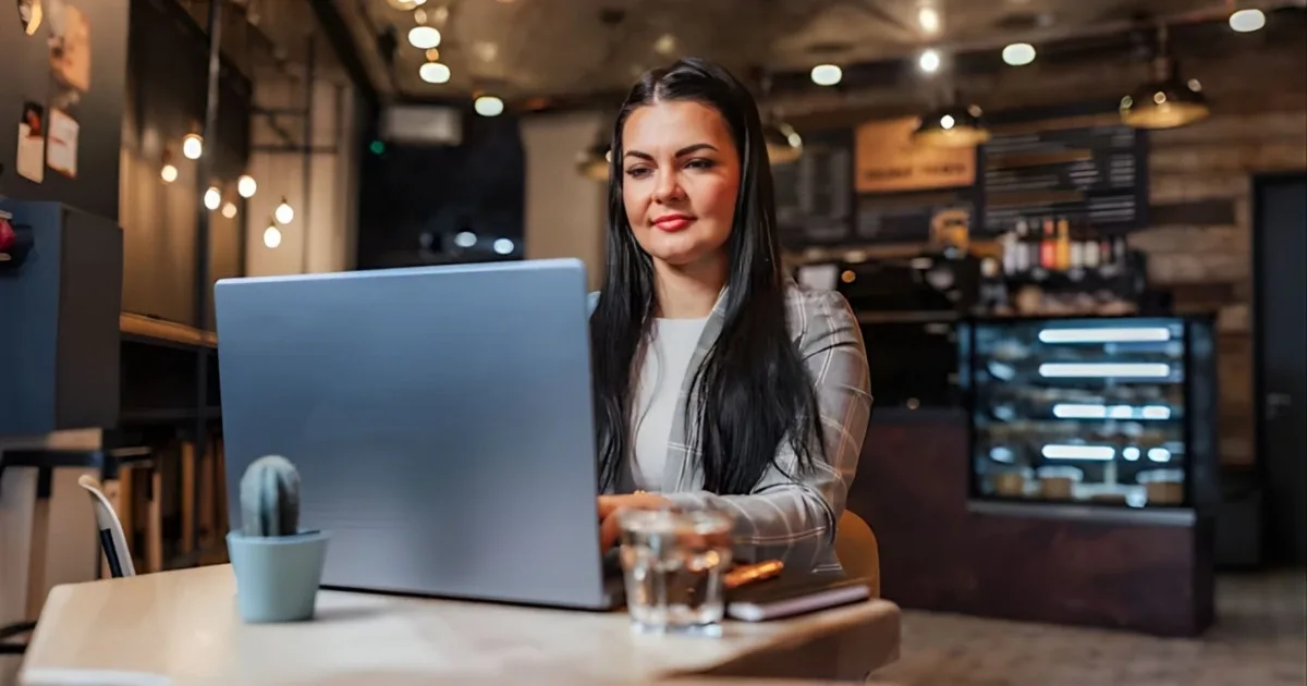 Eine Restaurantbesitzerin richtet ihr Online-Bestellsystem auf einem Laptop in ihrem Restaurant ein – die ersten Schritte zur Einführung eines Lieferservices für ein deutsches Restaurant