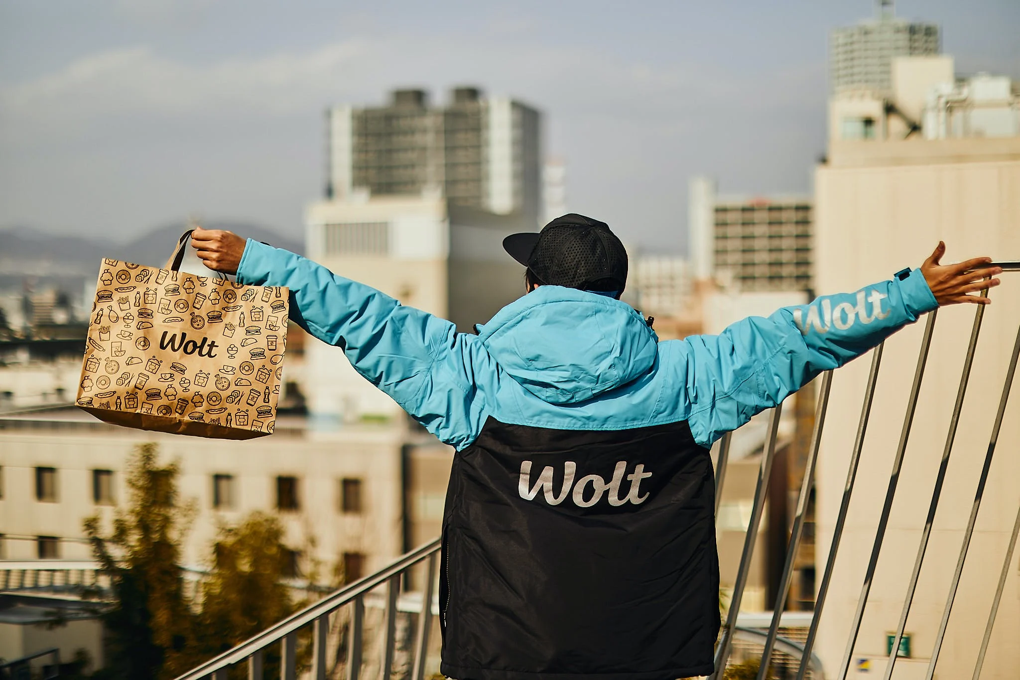 Wolt courier partner holding a wolt branded paper bag