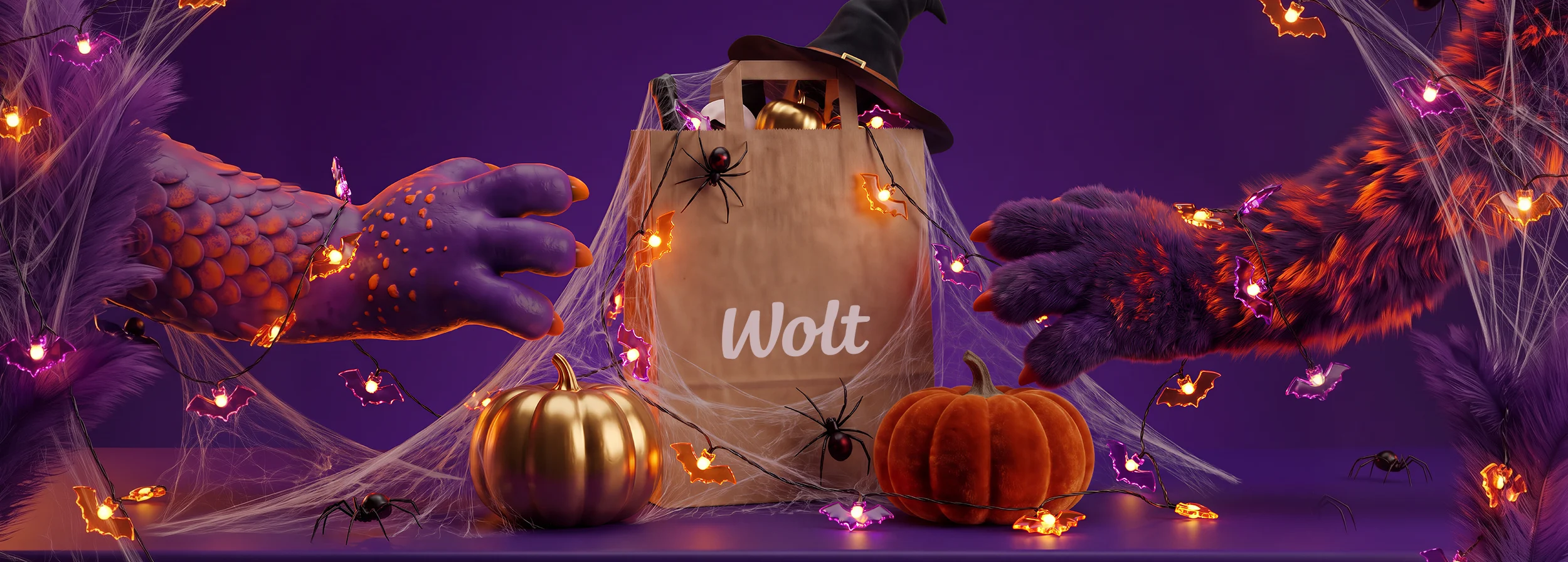 A Wolt paper delivery bag topped with a witch hat, decorated with spiderwebs, black spiders and glowing bat-shaped string lights, flanked by a golden pumpkin and an orange velvet pumpkin, with two monster hands reaching toward the bag from either side, on a purple background.