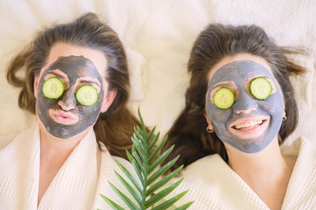 top-view-smiley-women-with-face-masks-cucumber-slices-their-eyes 23-2148520316