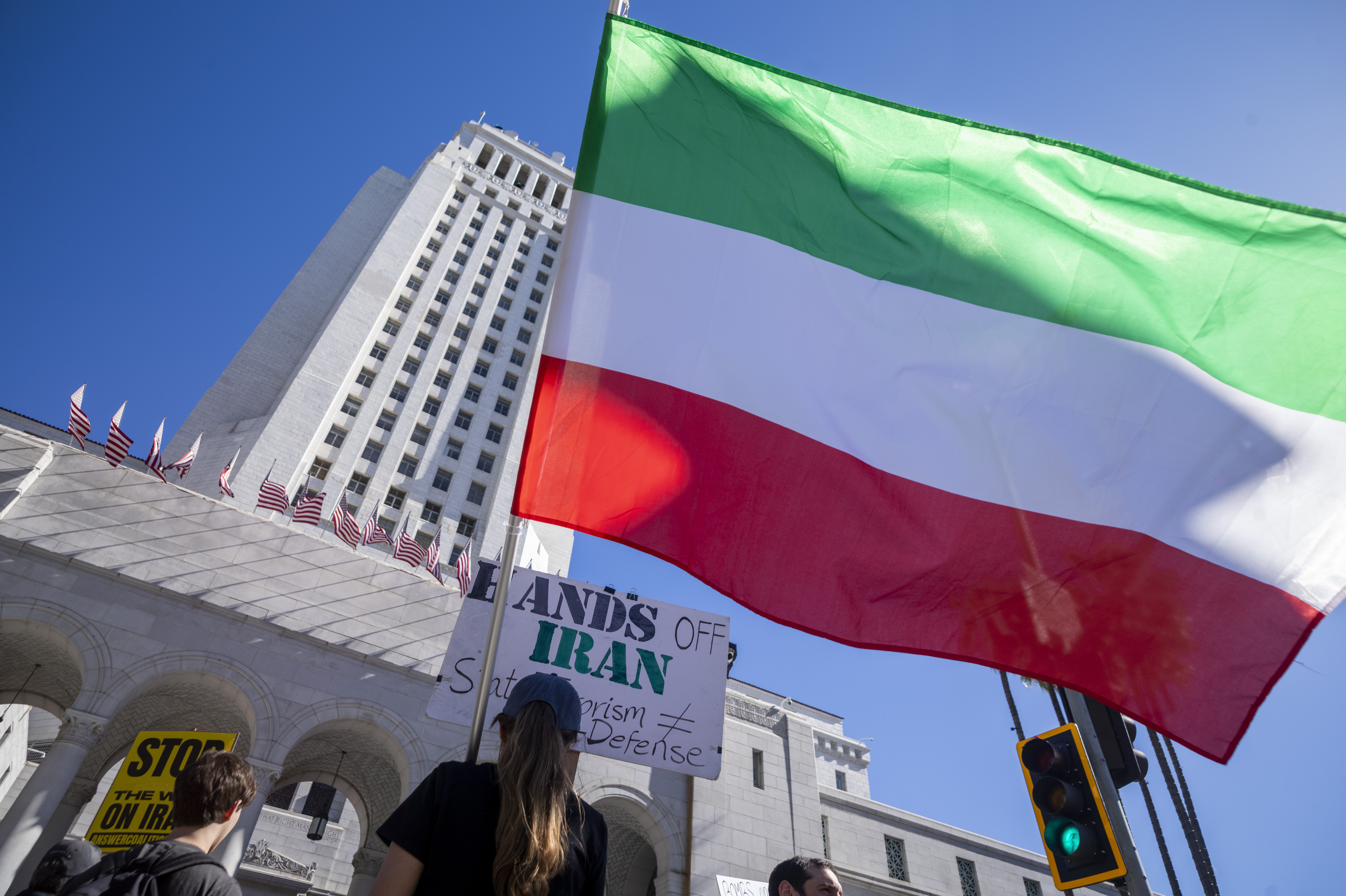 A handful of people protest with signs and flags outside LA City Hall in support of Iran