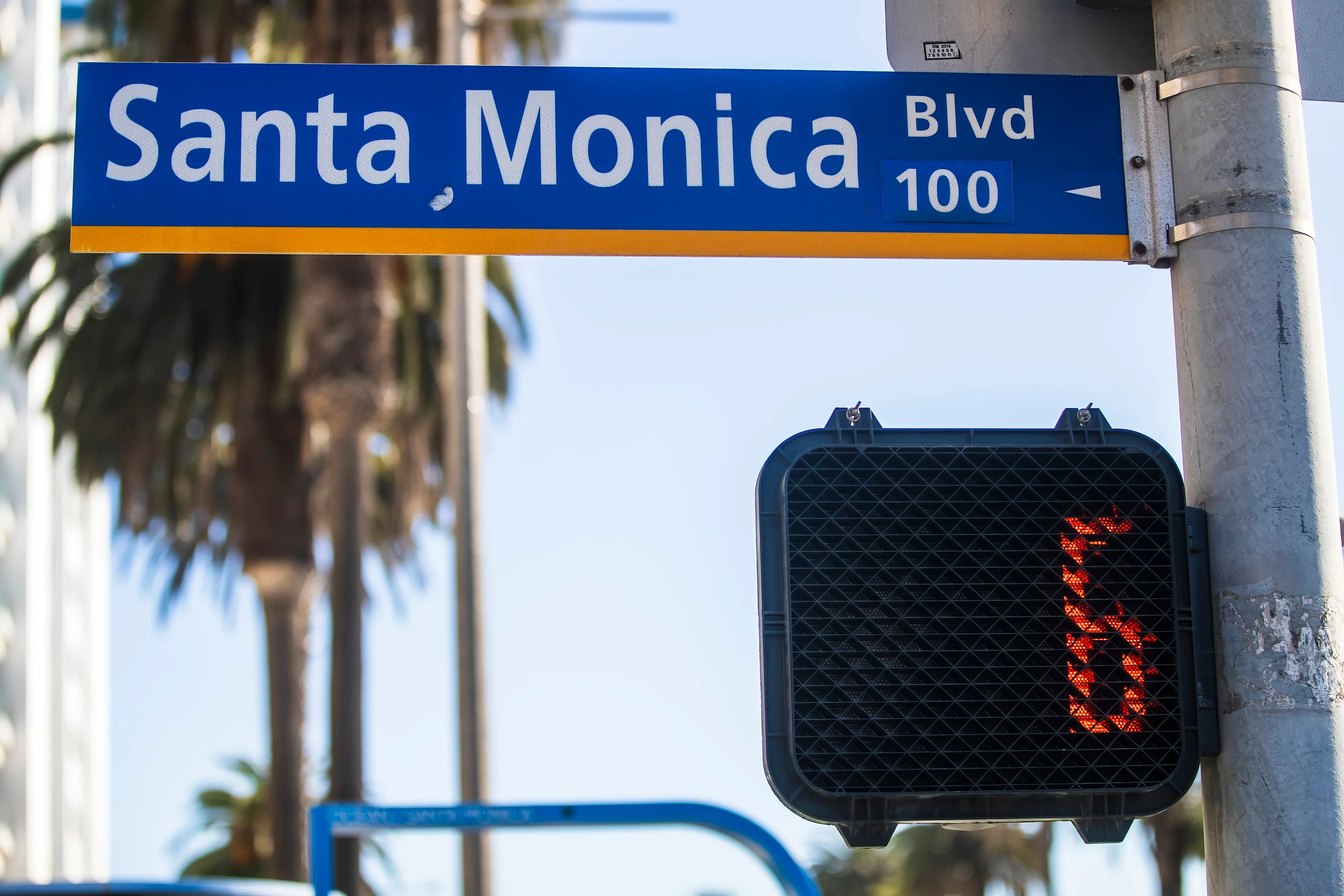 A Santa Monica Boulevard street sign hanging above a crosswalk sign.