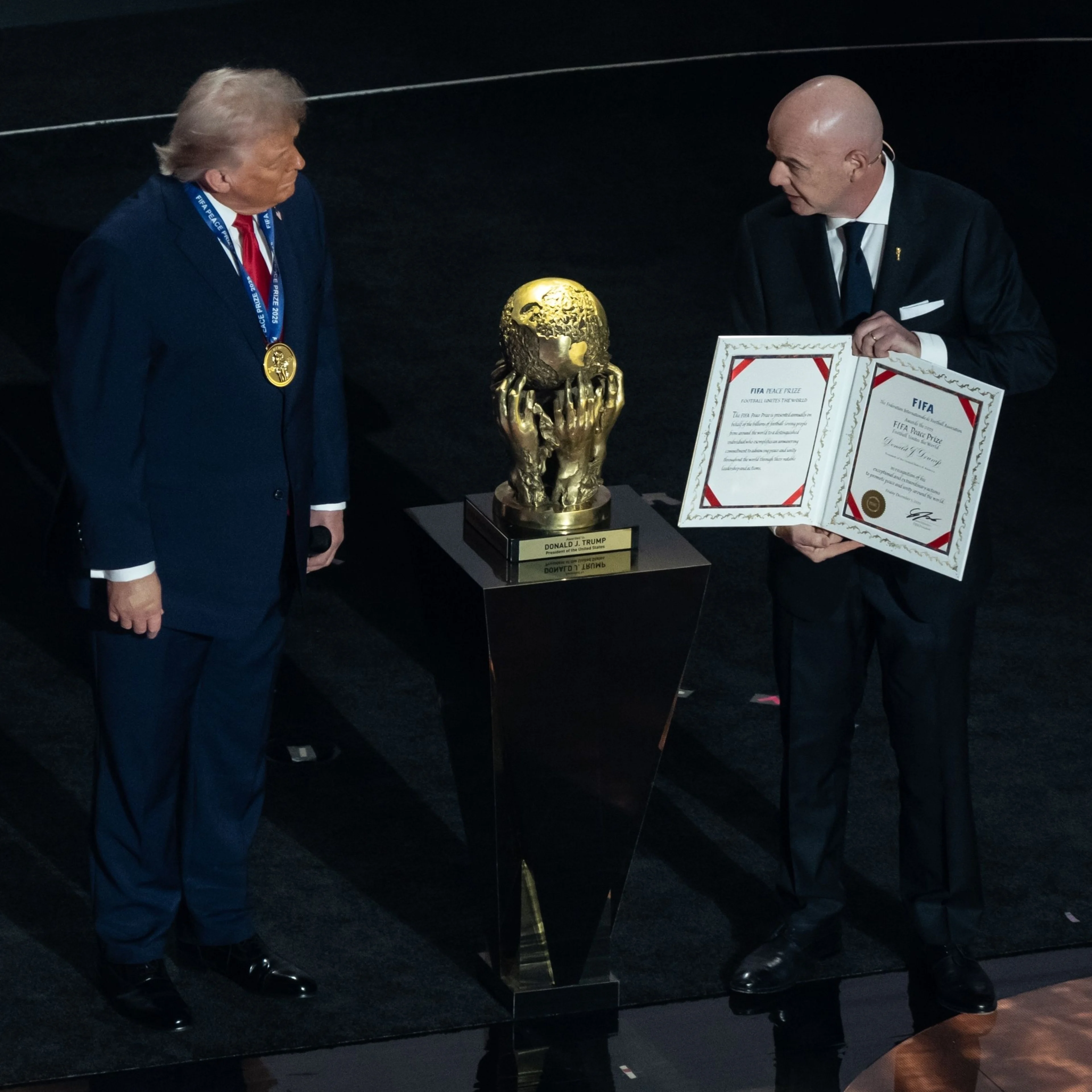 A bald man presents an award to another man