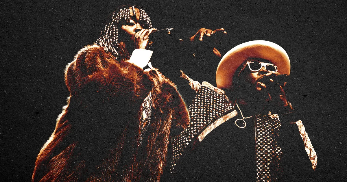 Two performers on stage; a woman in a fur coat holding a mic and a man in a wide-brim hat and patterned outfit.
