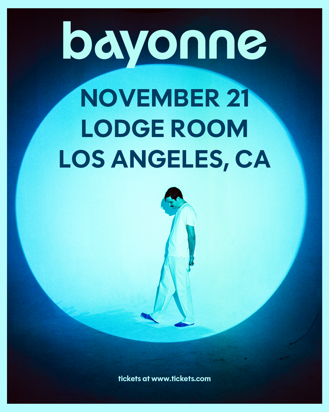 Bayonne concert poster for November 21 at Lodge Room, Los Angeles, CA, featuring a man in white walking in a blue spotlight.