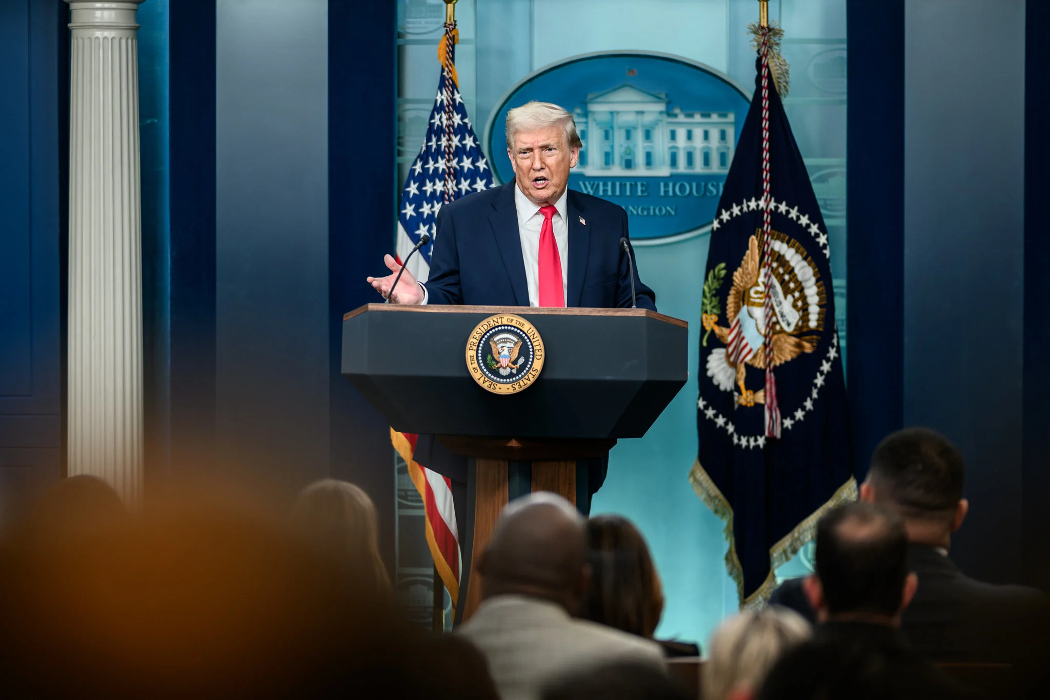 Man in a dark suit stands at a podium.