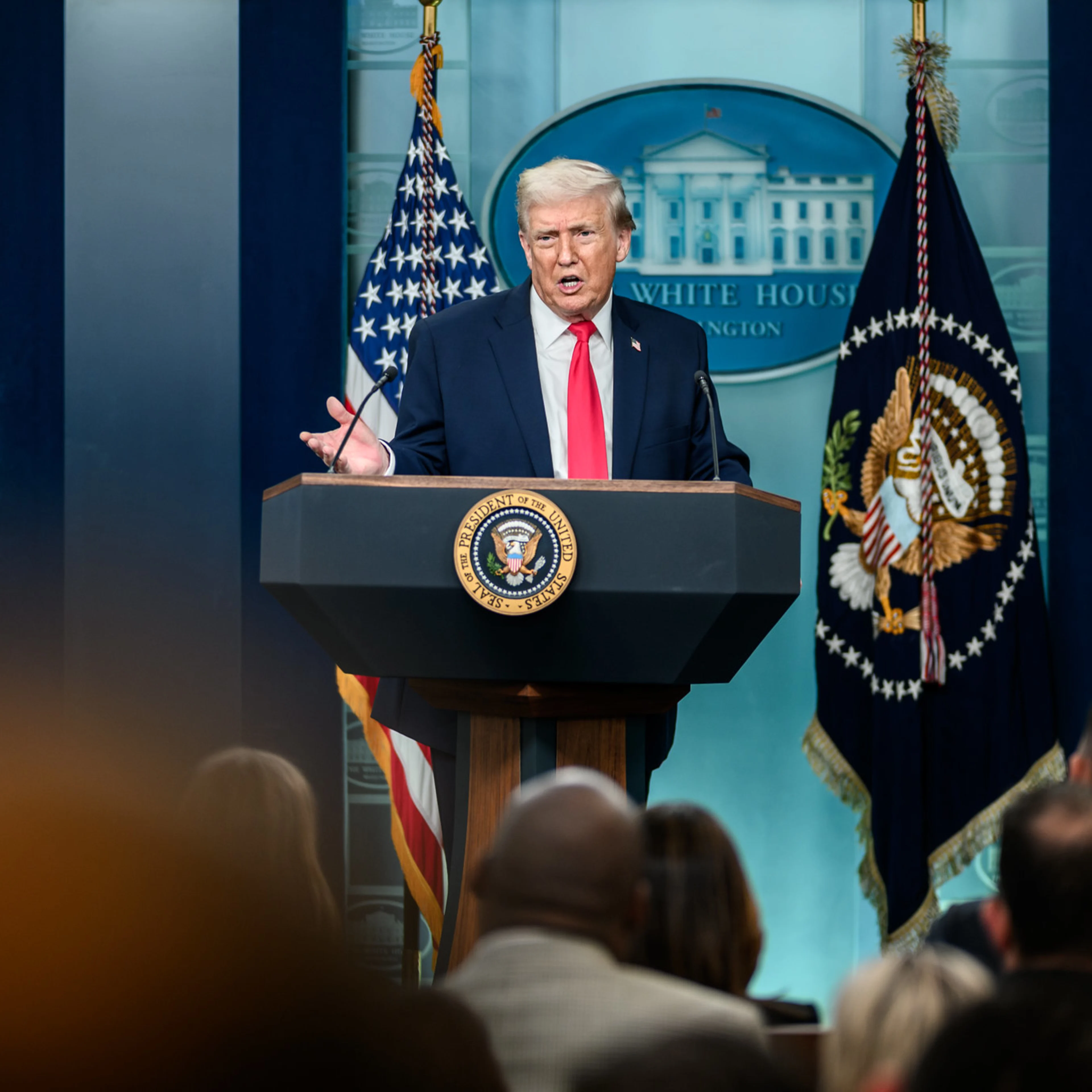 Man in a dark suit stands at a podium.