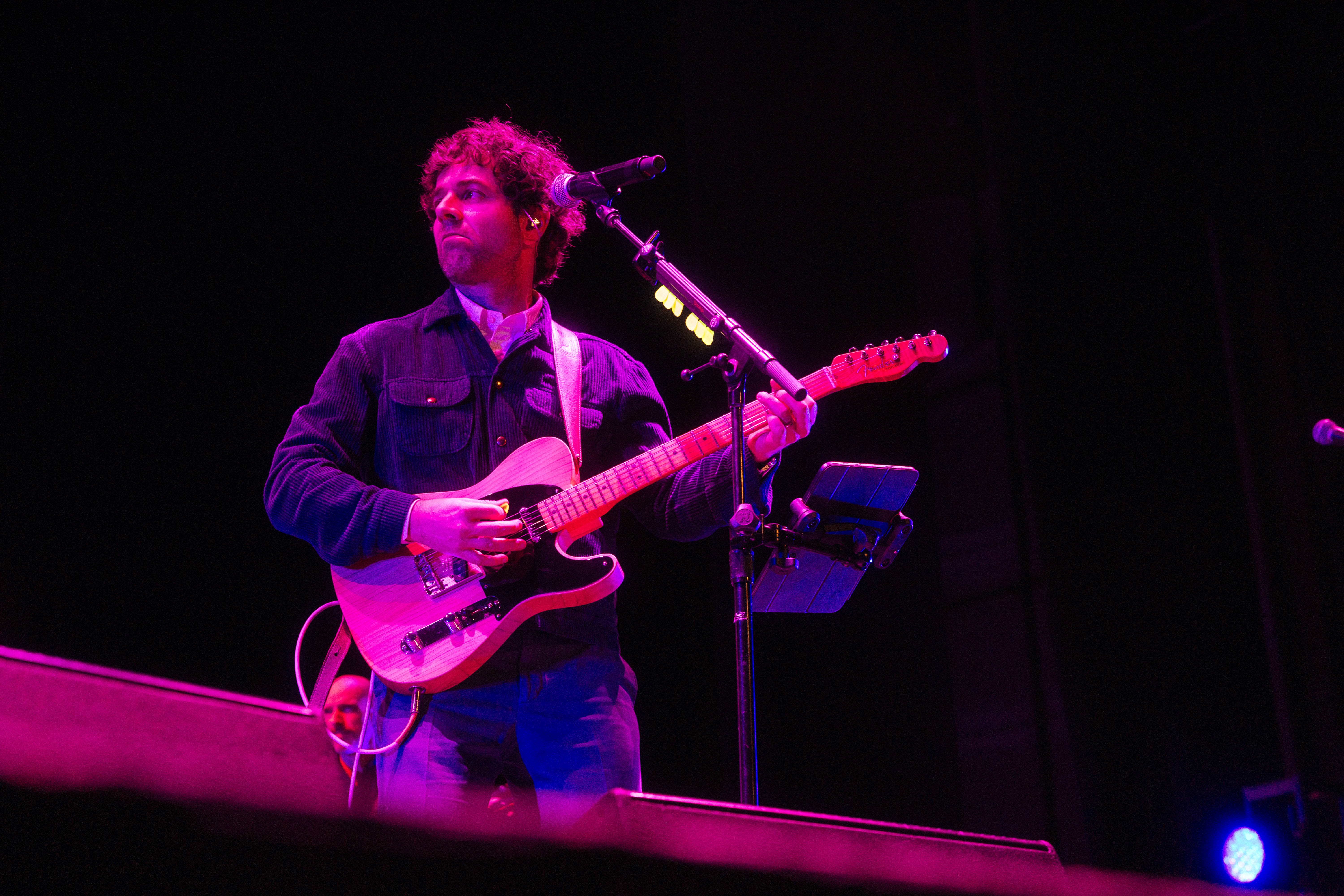 A bandleader plays a guitar on stage at a recent benefit concert.