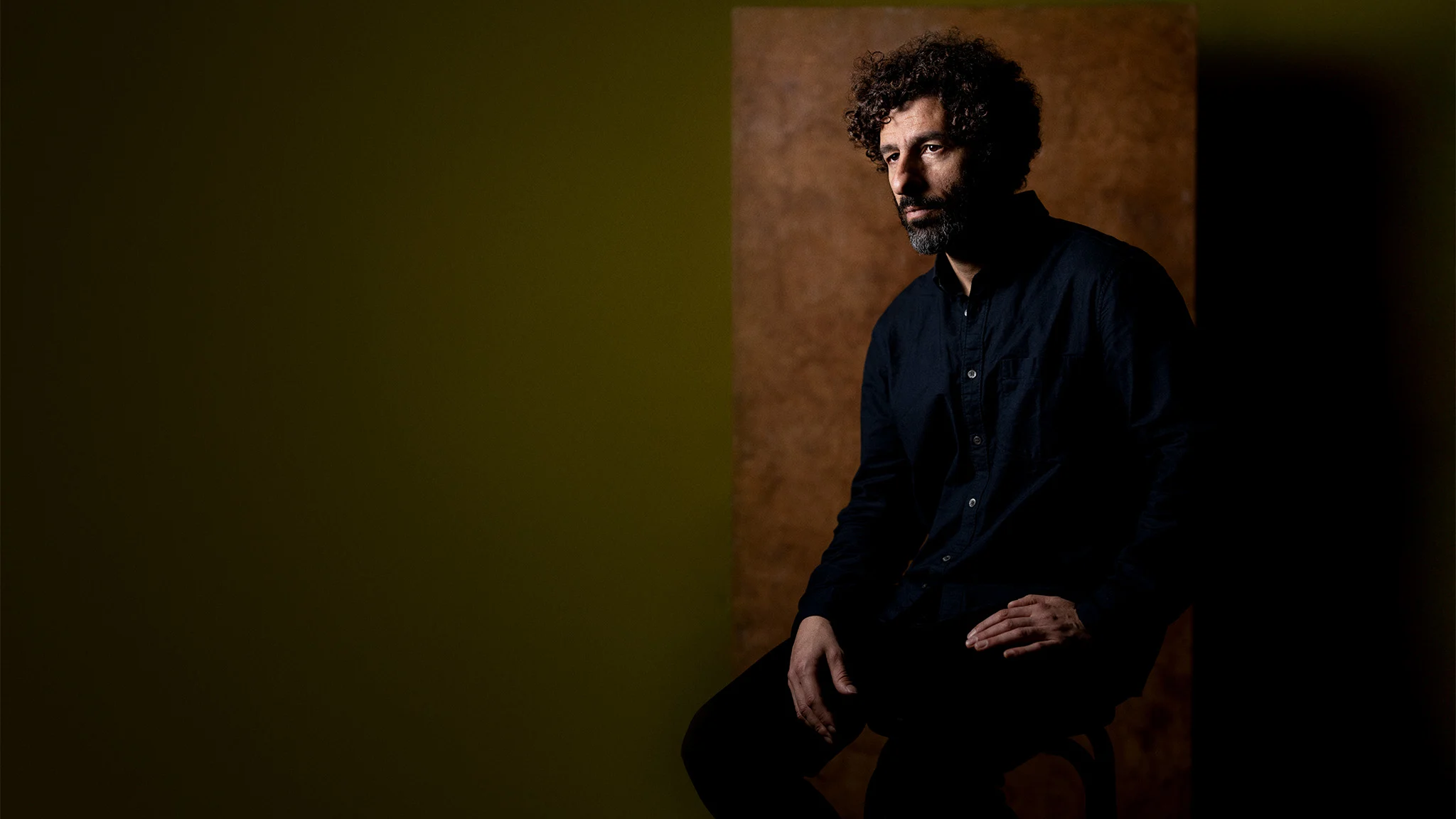 A photo of singer-songwriter José González sitting down facing towards the camera.