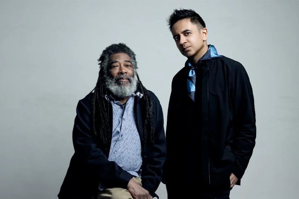 Photo of Vijay Iyer and Wadada Leo Smith against a gray background; one seated  the other standing.