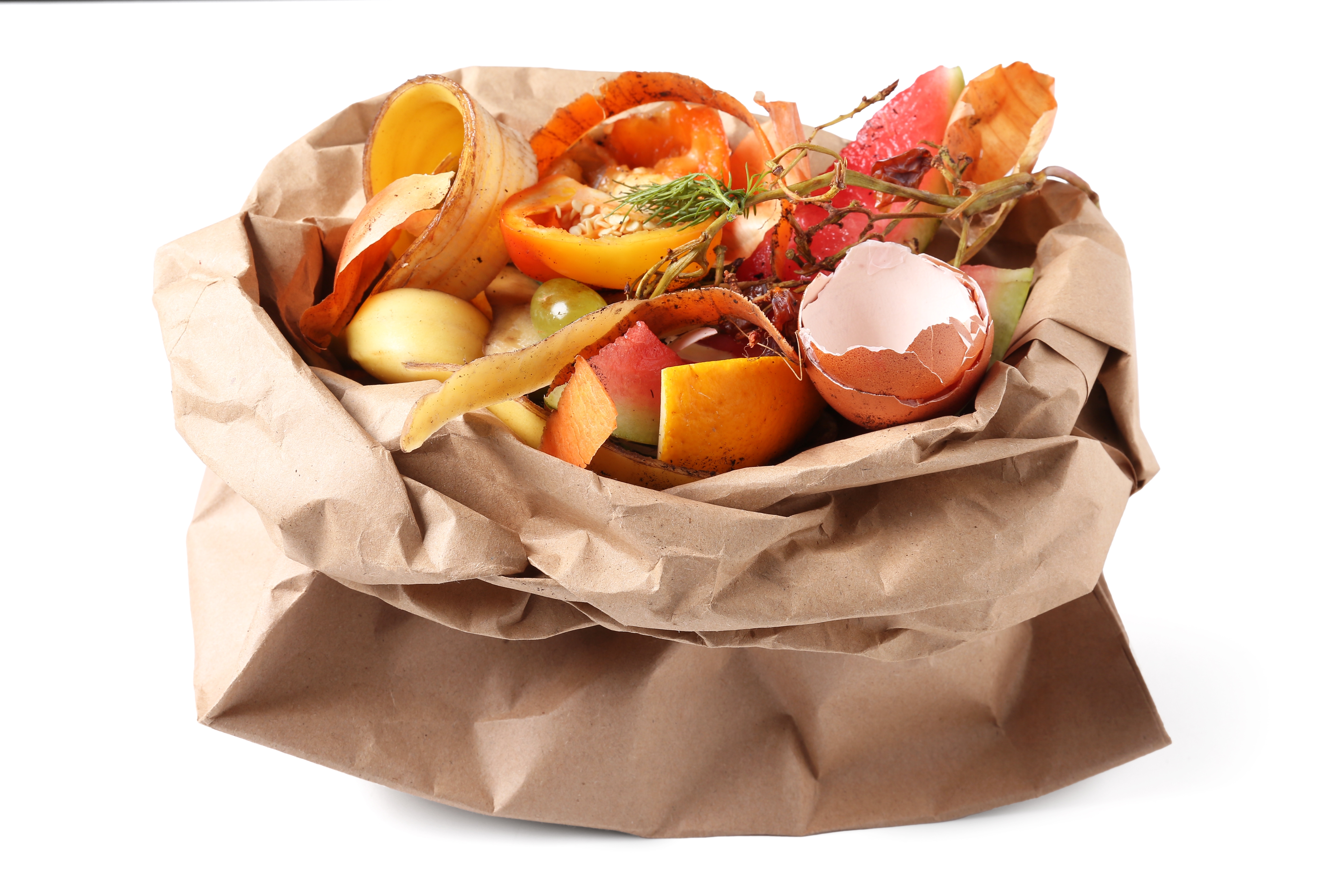 A brown paper bag filled with colorful food scraps including fruit peels, eggshells, and vegetable waste for composting.